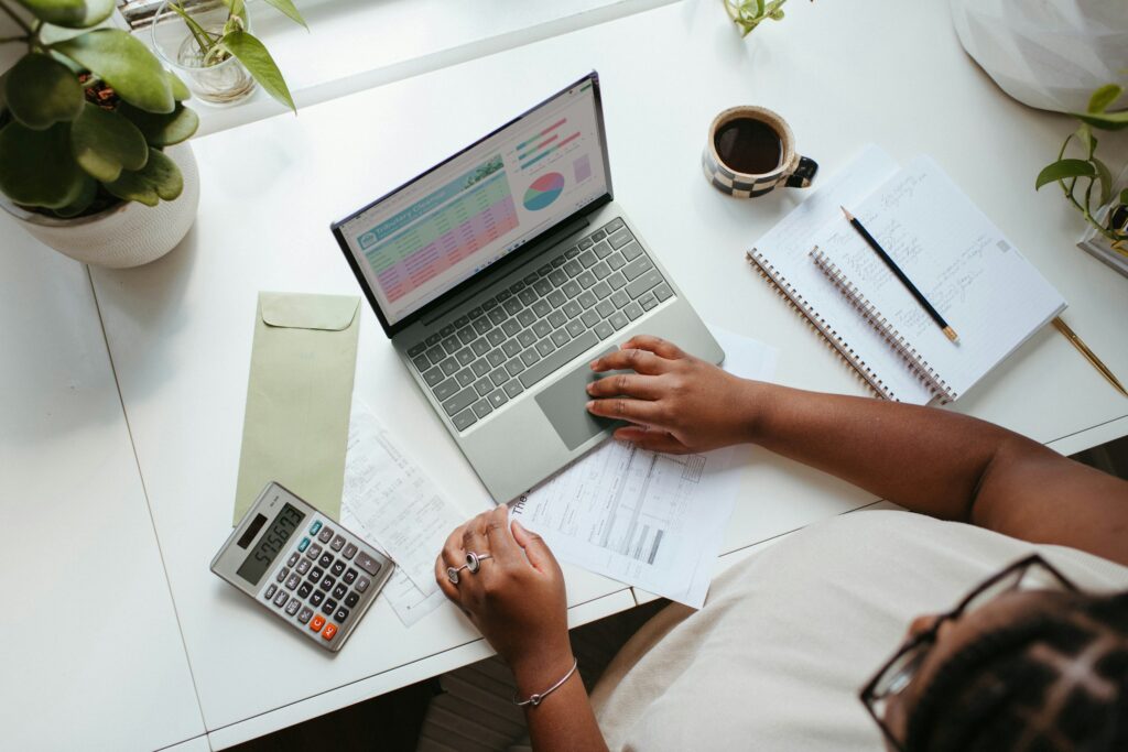 Professional managing payroll records with a laptop, calculator and business documents